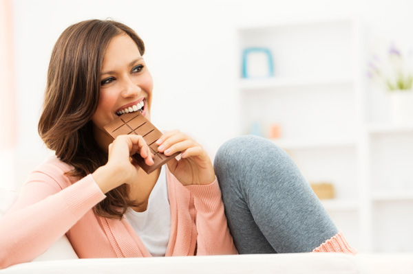 happy-woman-taking-bite-of-chocolate-bar